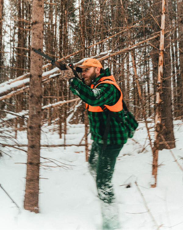 Man wearing Big Woods Bucks brand wool hunting jacket in snowy forest. 